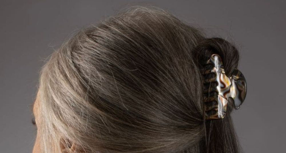 Woman with long natural grey hair in a half-up style, held with a TEGEN claw clip