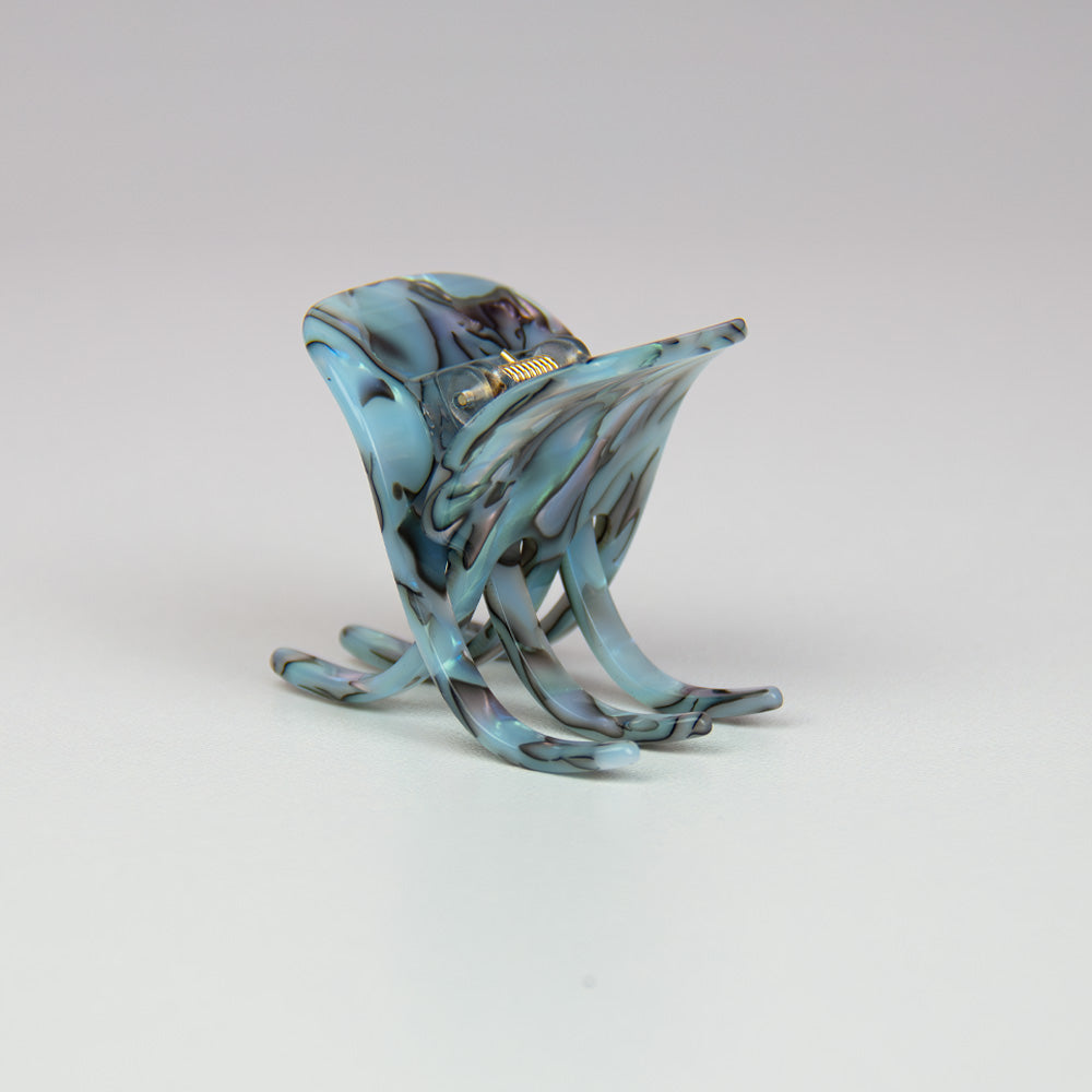 Marbled opal hair claw on a light gray background from side
